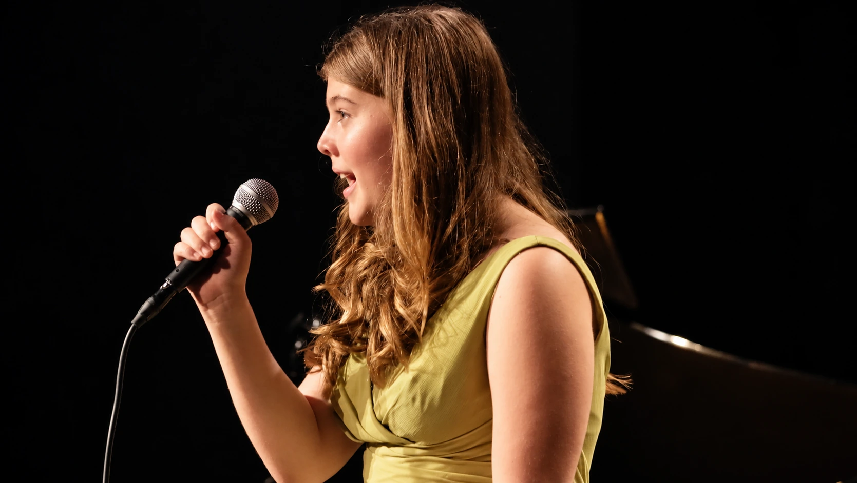 Young singer holding a microphone on an MBMS stage